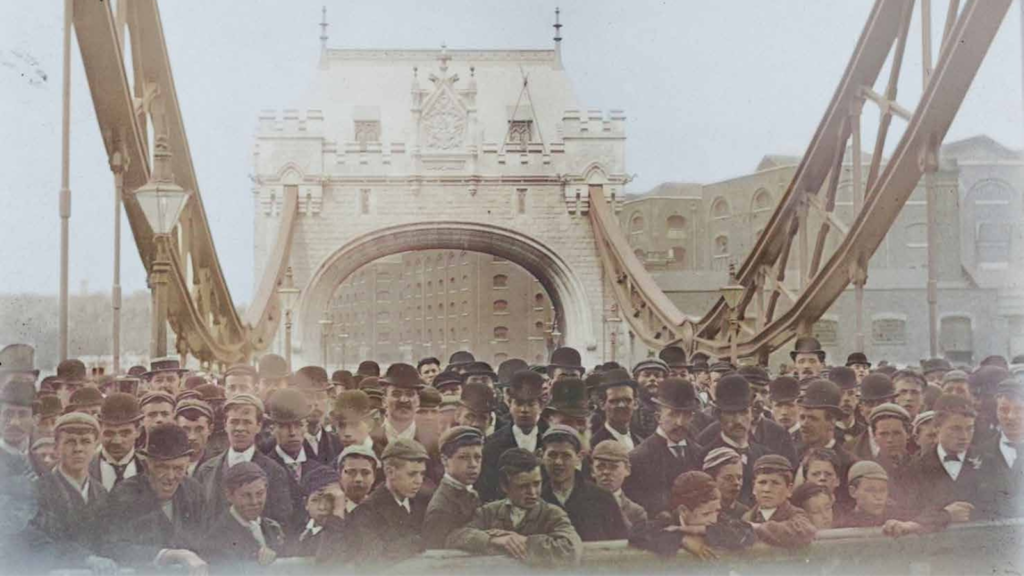A sepia photograph of a crowd of men and boys waiting for the public opening of Tower Bridge in 1894.