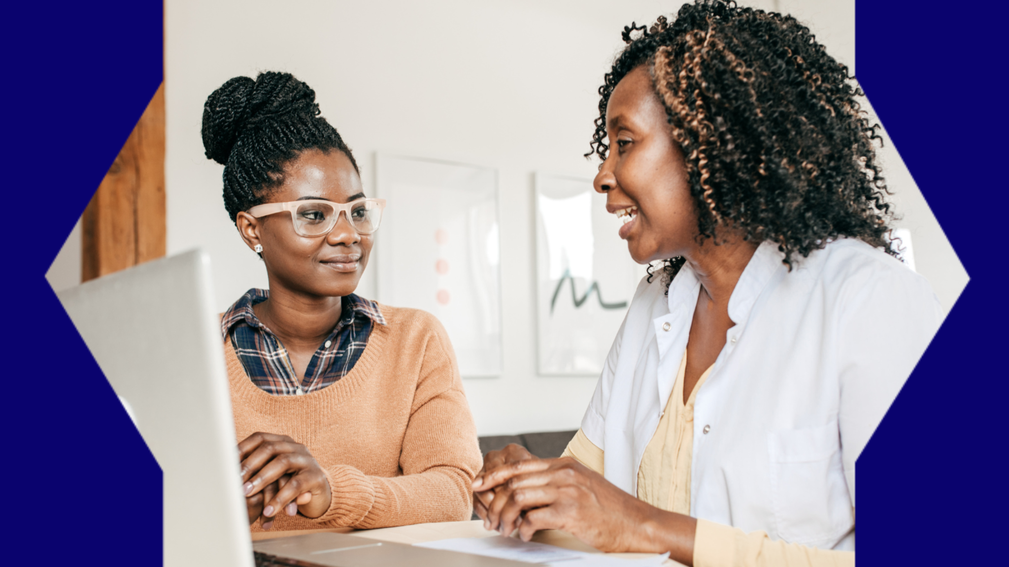 Two women discussing work over a laptop computer.